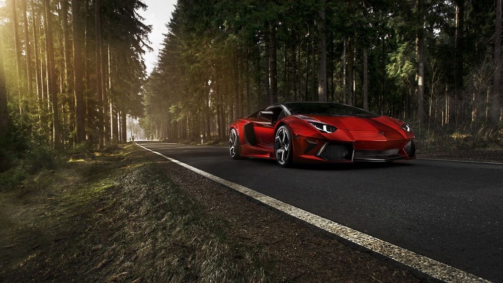 Обои для рабочего стола Красная Lamborghini Aventador на дороге среди леса