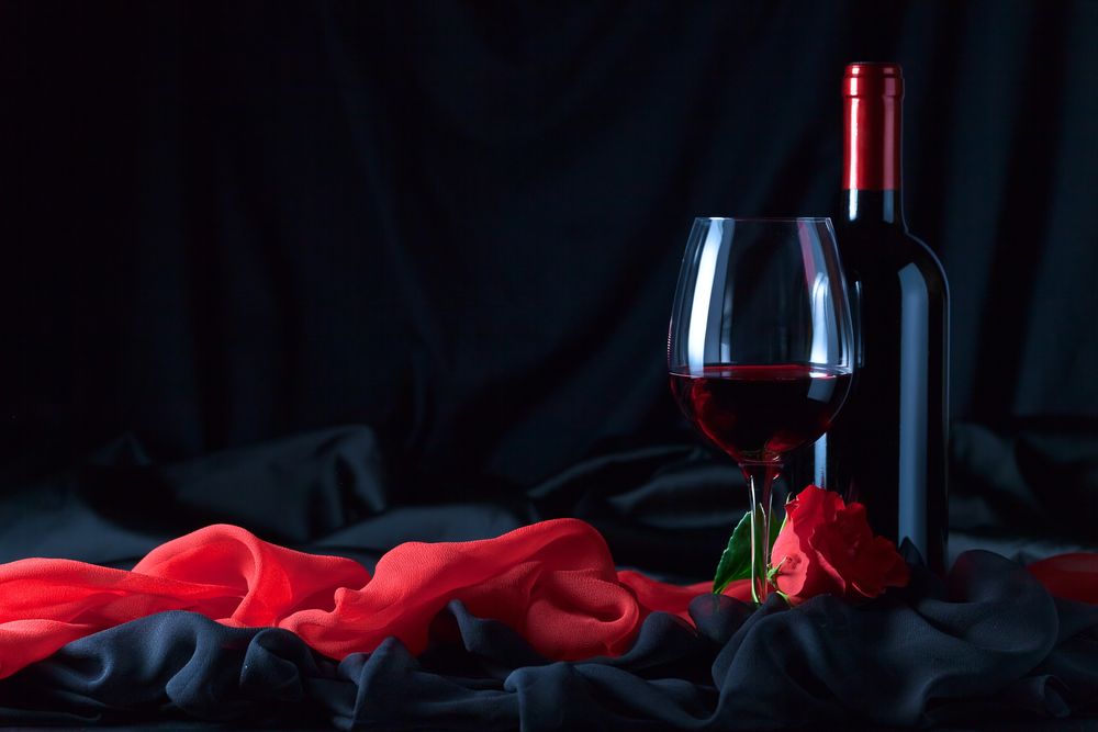 Обои для рабочего стола Бокал с вином, бутылка и роза на черной и розовой ткани