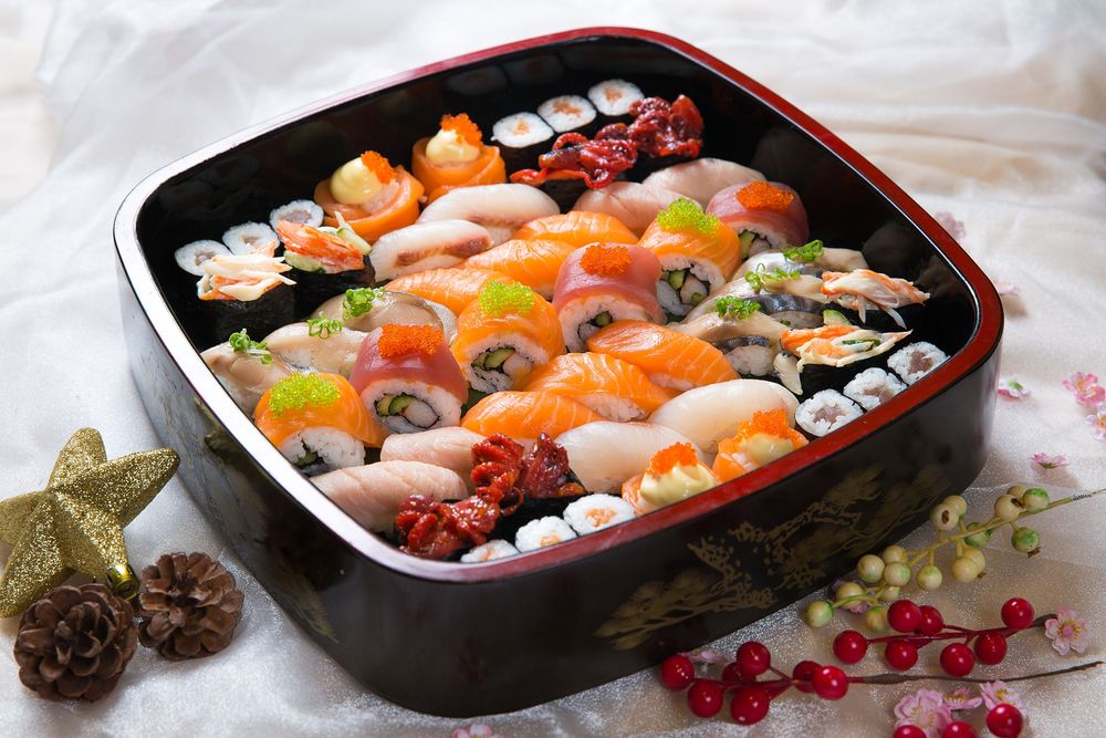 Обои для рабочего стола Японская кухня: бенто с ассорти из рисовых роллов и суши с рыбой, икрой и огурцом, рядом шишки, звезда и ягодки на ветке