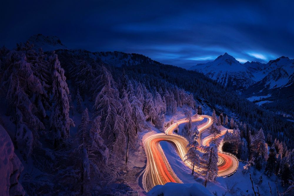 Обои для рабочего стола Подсветка на серпантине в горах зимней ночью, горный перевал Malojapass, Switzerland / Малояпас, Швейцария, фотограф Roberto Sysa Moiola