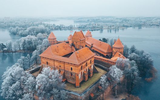 Обои на рабочий стол Тракайский замок / Trakai Castle в окружении заснеженных деревьев и озера, Литва / Lithuania, фотограф Andrius Aleksandraviсius