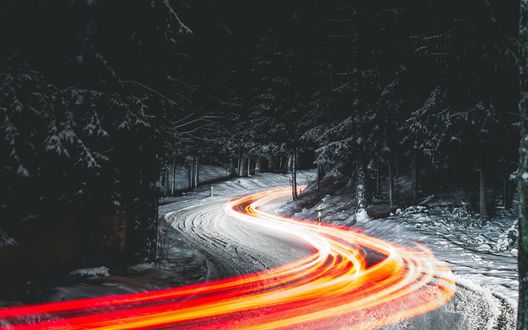Обои на рабочий стол Огни на дороге, ведущей через заснеженный лес