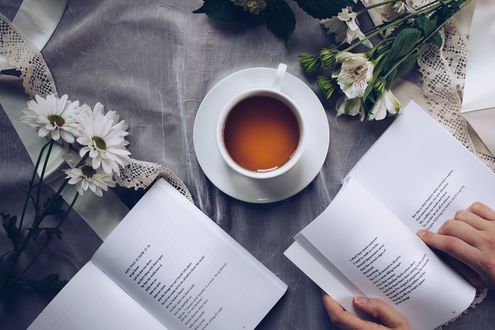 Обои на рабочий стол Чашка кофе на блюдце, ромашки и открытые книги на столе