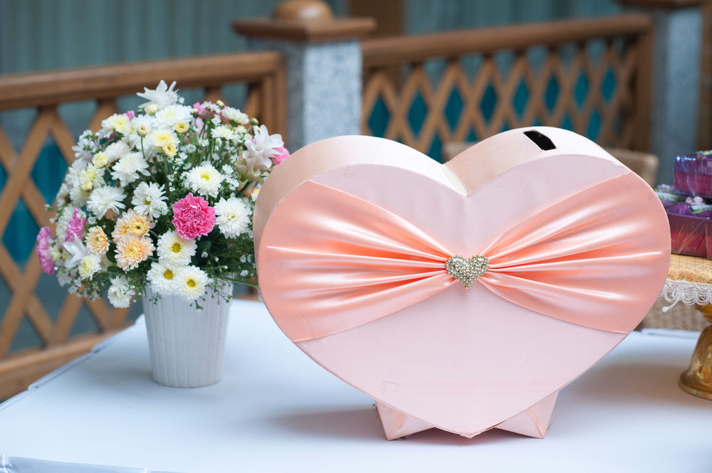 Обои для рабочего стола Букет хризантем на белом столе, рядом подарочная коробка в форме сердца розово-кремового цвета