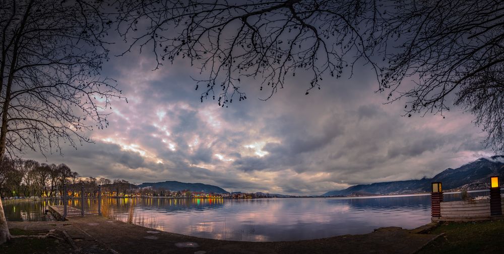Обои для рабочего стола Озеро Иоанина, Греция / Ioannina lake, Greece, вечер под пасмурным небом, вдали огни города, by Atlanatios Atlantas