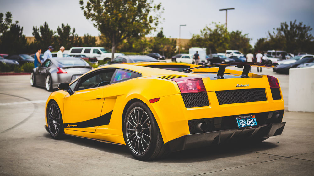 Обои для рабочего стола Желтый Lamborghini Aventador стоит на парковке
