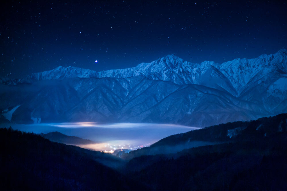 Обои для рабочего стола Огни света в долине, среди заснеженных гор, покрытые ночным туманом, работа Сириус на горном хребте, автор Shinichiro Saka