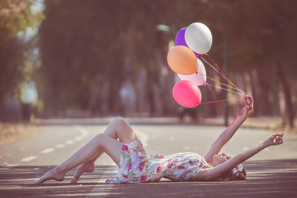 Обои для рабочего стола Девушка лежит на дороге с воздушными шариками