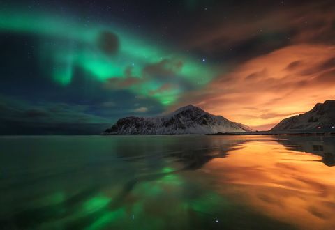 Обои на рабочий стол Полярное сияние спорит с засветкой от города Leknes, Lofoten, Norway / Лекнес, Лофотен, Норвегия, фотограф Сутковой Сергей