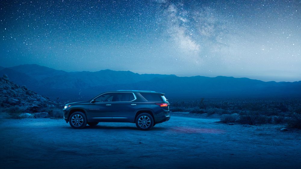 Обои для рабочего стола Автомобиль Chevrolet Traverse стоит на фоне гор звездной ночью