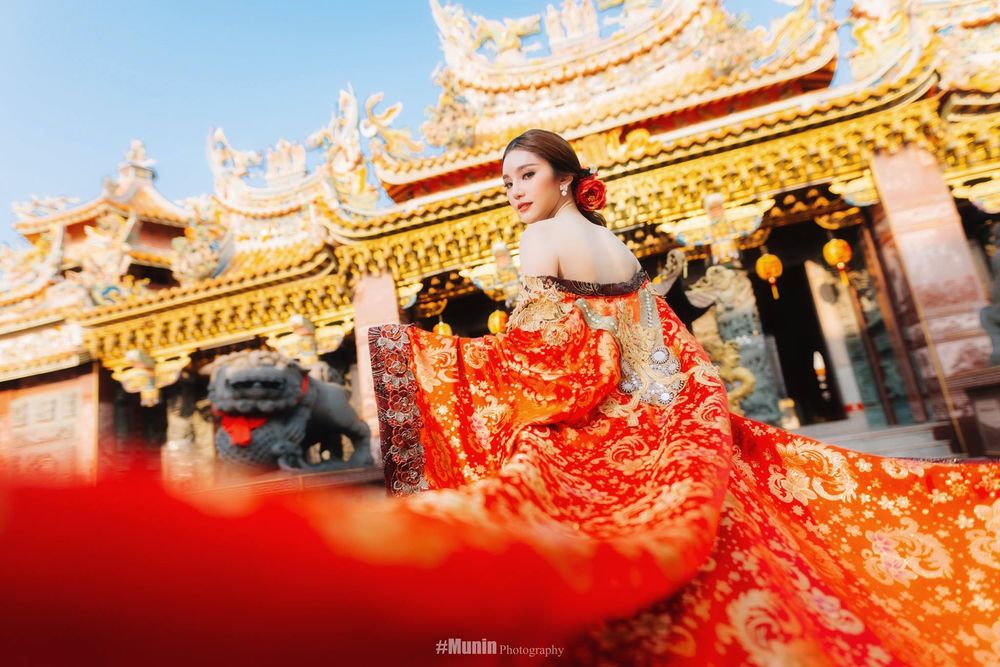 Обои для рабочего стола Азиатка китаянка в красном платье стоит в пол-оборота на фоне храма с позолоченной крышей