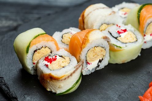 Обои на рабочий стол Японская кухня: роллы с лососем, огурцом и икрой на черной поверхности
