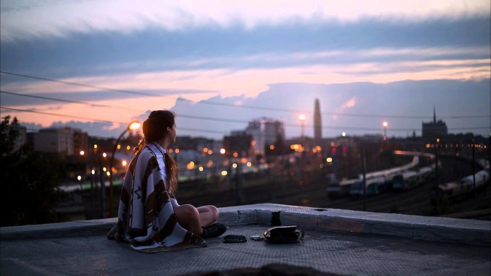Обои для рабочего стола Девушка сидит на крыше здания железнодорожного депо
