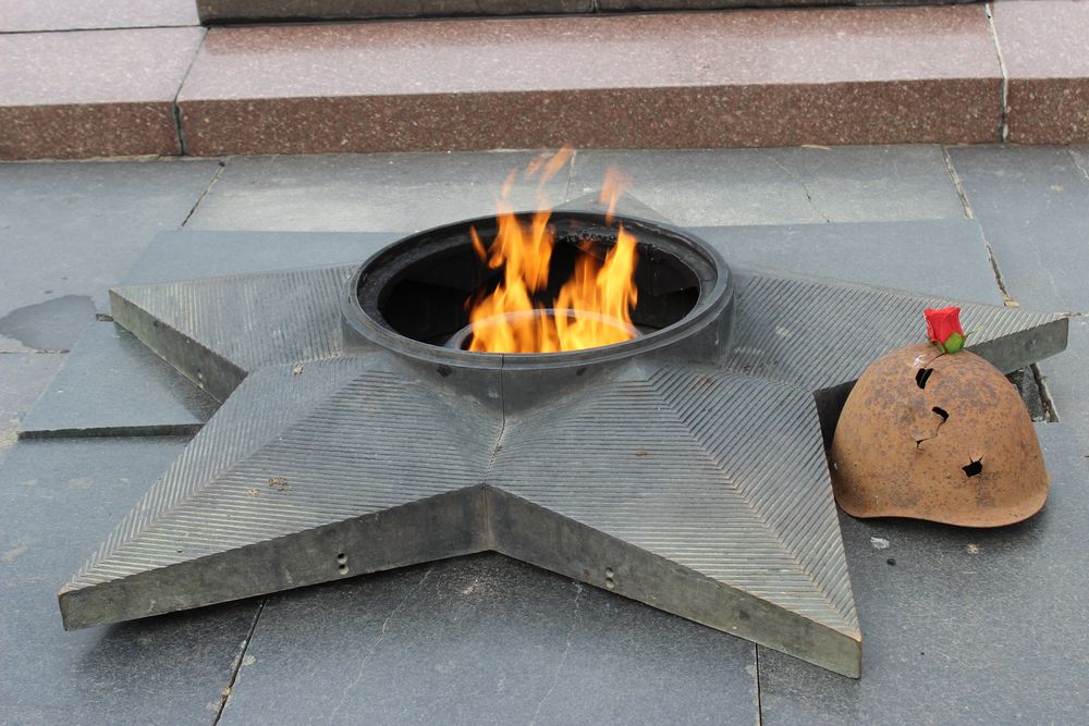 Обои для рабочего стола Вечный огонь в пятиконечной звезде, простреленная каска с алой розой, мемориал Сталинградская битва, фотограф Александр Жданенко