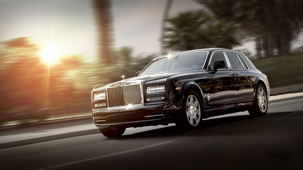 Обои для рабочего стола Rolls Royce едет на фоне солнца