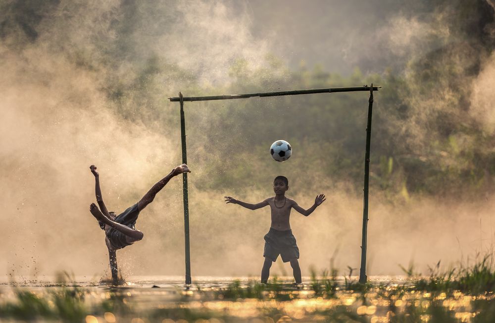Обои для рабочего стола Мальчишки играют в футбол, в воде, покрытой туманом, by Sasin Tipchai
