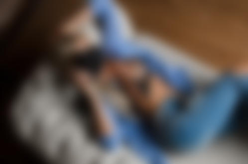 Обои для рабочего стола Девушка в джинсах и расстегнутой рубашке, с фотоаппаратом в руке, лежит на диване, фотограф Dim Khokhlov