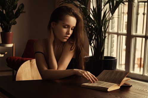 Обои на рабочий стол Модель Феникс Райа сидит за столом с книгой. Фотограф Томашев Сергей