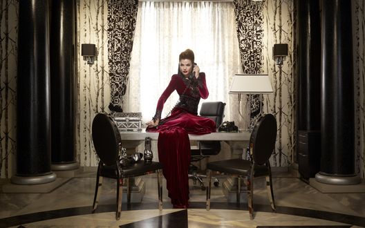 Обои на рабочий стол Американская актриса Лана Паррия в образе Злой Королевы из сериала Однажды в Сказке (Once Upon a Time) сидит на столе и разговаривает по телефону