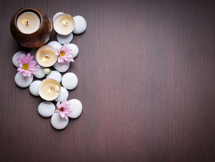 Обои на рабочий стол Spa-набор: зажженные свечи, белые камешки и розовые цветы на деревянной поверхности