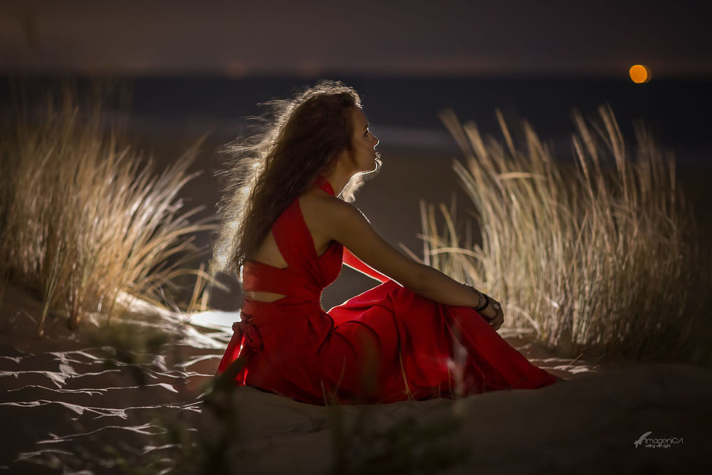 Обои для рабочего стола Девушка в красном платье сидит на песке, фотограф Antonio A Conde