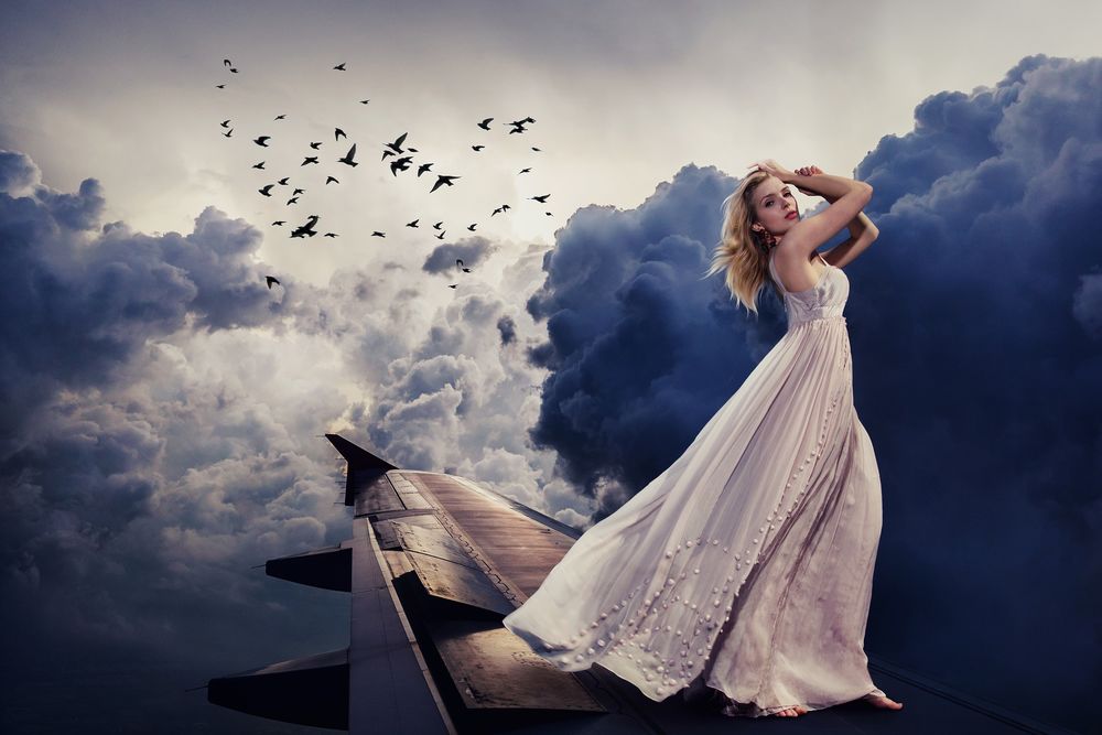 Обои для рабочего стола Девушка в длинном белом платье стоит на крыле самолета, by Sarah Richter