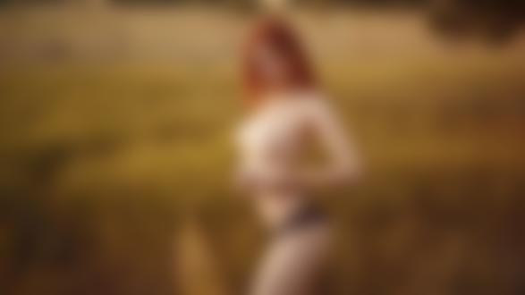 Обои для рабочего стола Обнаженная рыжеволосая девушка позирует, стоя в поле с высокой травой