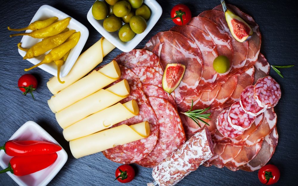 Обои для рабочего стола Разнообразие мясной и колбасной нарезки, помидоры - черри, оливки, красный и желтый перчик, и ломтики сыра