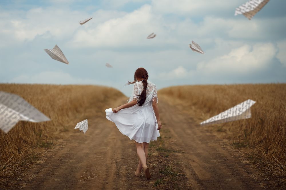 Обои для рабочего стола Девушка в белом платье идет по дороге в окружении бумажных самолетиков, фотограф Monica Lazar