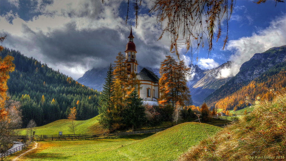 Обои для рабочего стола Obernberg am Brenner осенью с церковью Святого Николая, на заднем плане горы Tribulaune, Австрия. Фотограф Karl von Hilber