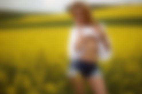 Обои на рабочий стол Модель мисс Марципанка в джинсовых шортах стоит на фоне цветочного поля. Фотограф Ника Мельн