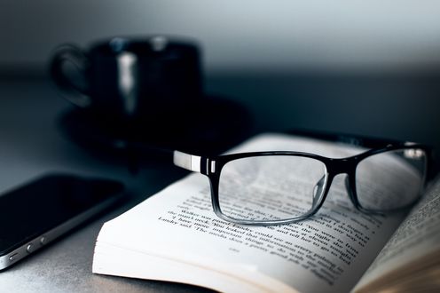 Обои на рабочий стол Очки лежат на книге рядом с кружкой и телефоном