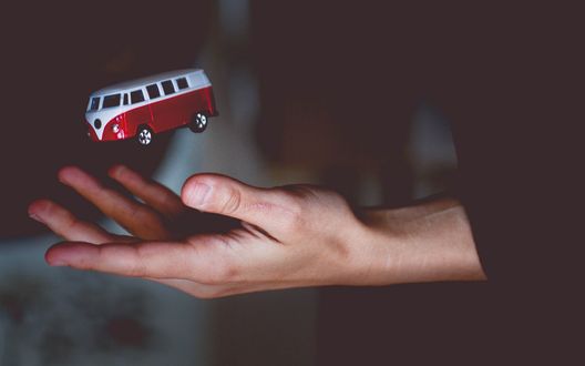 Обои на рабочий стол Мужская рука ловит маленький игрушечный автобус