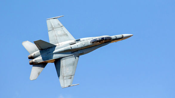 Обои на рабочий стол Летящий истребитель CF-18 Hornet на фоне голубого неба