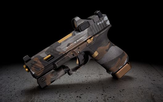 Обои на рабочий стол Модифицированный пистолет Glock в пустынном камуфляже на темном фоне