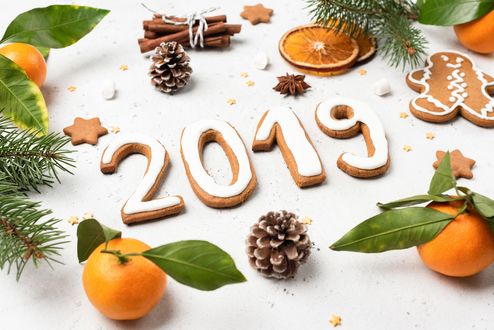 Обои на рабочий стол Цифры 2019 года из печенья на столе с шишками, палочками корицы, мандаринами и елочными ветками. Фотограф Владислав Носик