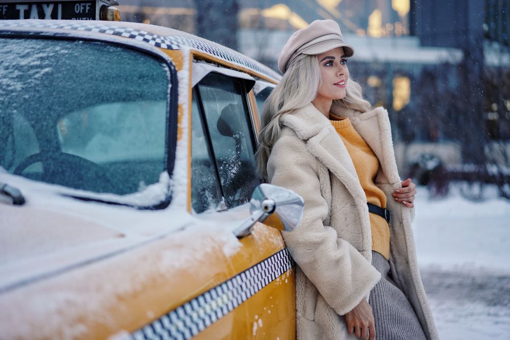 Обои для рабочего стола Девушка - блондинка стоит у такси в снегу, фотограф Sergei Churnosov