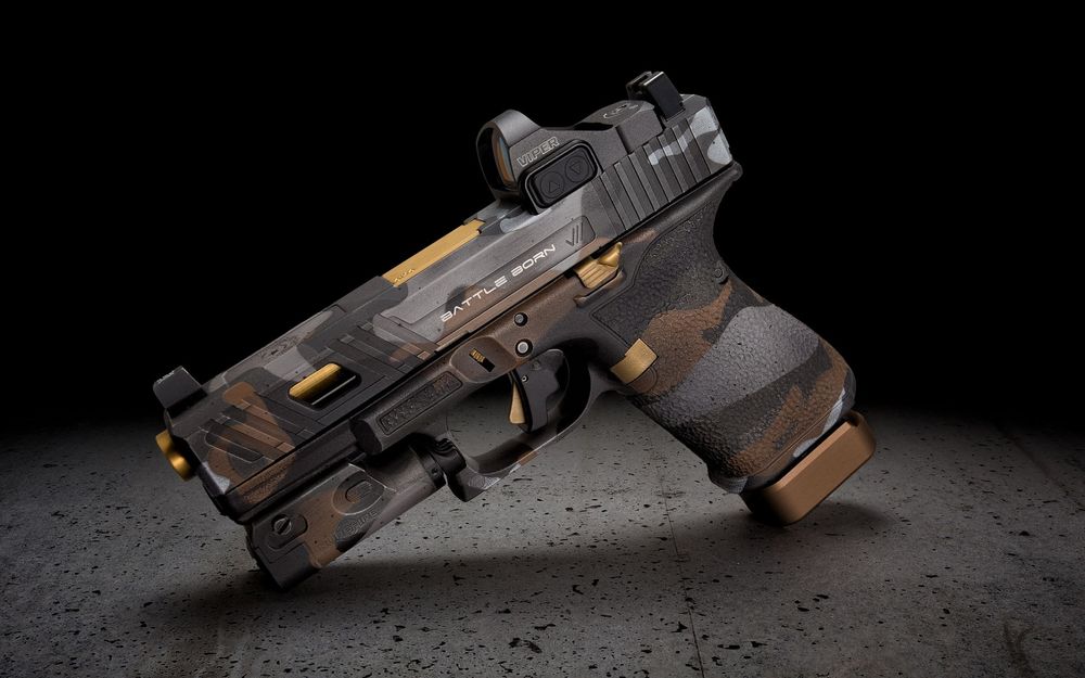 Обои для рабочего стола Модифицированный пистолет Glock в пустынном камуфляже на темном фоне