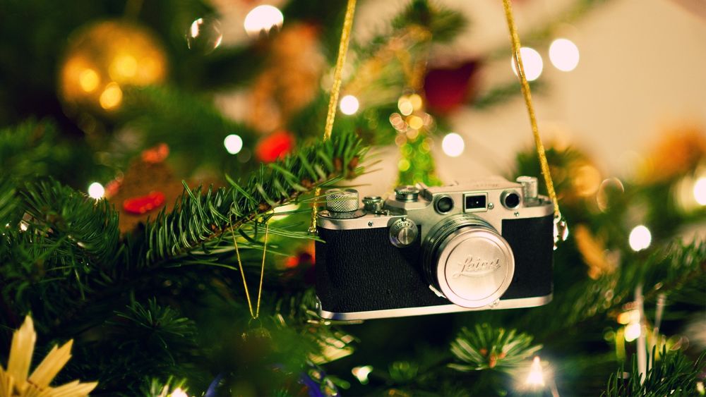 Обои для рабочего стола Фотоаппарат висит на ветке новогодней елки