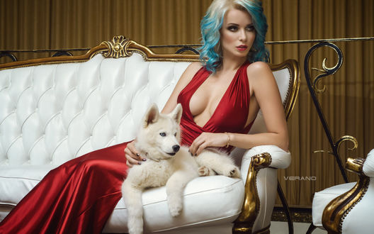 Обои на рабочий стол Модель Ekaterina Enokaeva / Екатерина Енокаева в красном платье с глубоким декольте сидит на диване с собакой. Фотограф Николас Верано