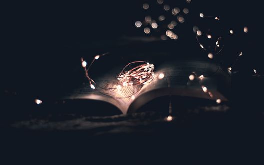 Обои на рабочий стол Гирлянда лежит на книге в темноте