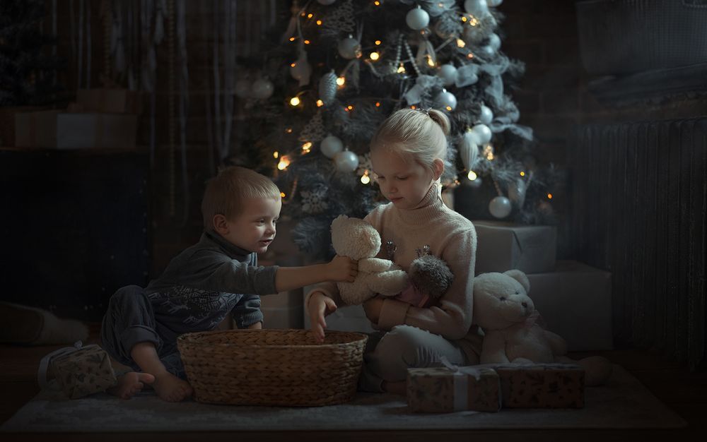 Обои для рабочего стола Мальчик и девочка сидят с игрушками перед елкой. Фотограф Elena Mironova