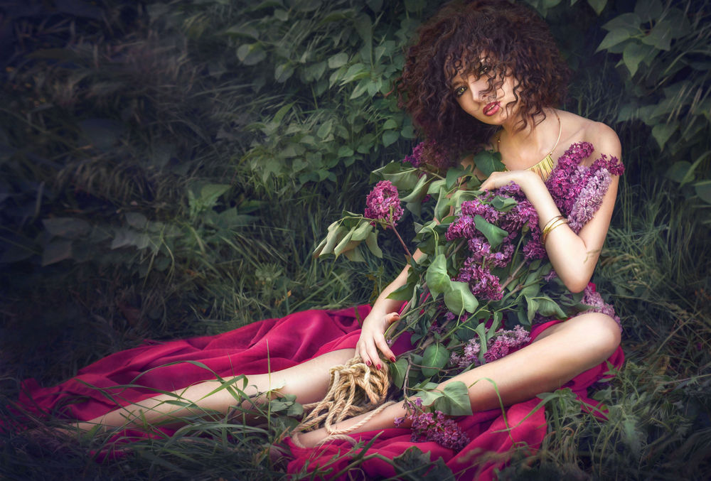 Обои для рабочего стола Девушка сидит с сиренью в руках у куста. Фотограф Ilona