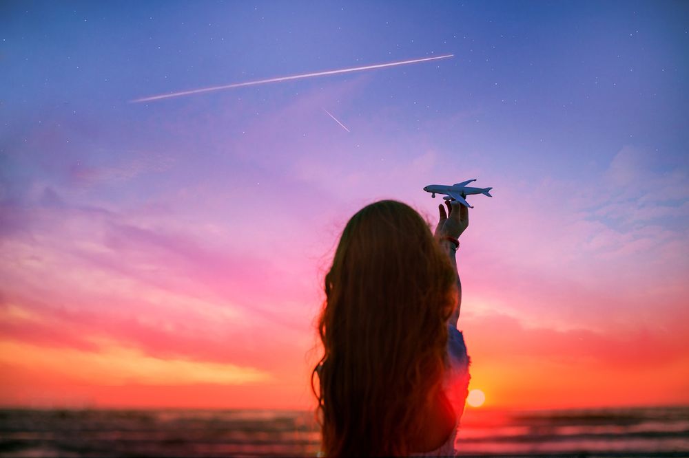Обои для рабочего стола Девушка держит модель самолета в руке на фоне неба во время захода солнца, by Alla Simacheva