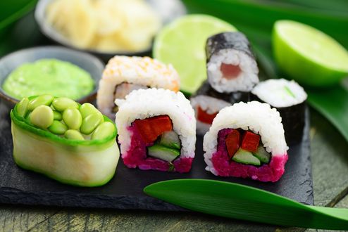 Обои на рабочий стол Японская кухня: роллы со свеклой, огурцом и морковью, рядом васаби и лайм на листьях бамбука