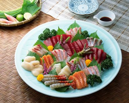 Обои на рабочий стол Японская кухня: блюдо с ассорти из морепродуктов и нарезки из разных сортов рыбы, рядом зелень и соевый соус