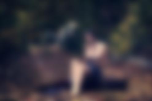 Обои для рабочего стола Полуобнаженная темноволосая девушка с косичками сидит на чемодане на проселочной дороге, на фоне природы. Фотограф Игорь Вьюшкин