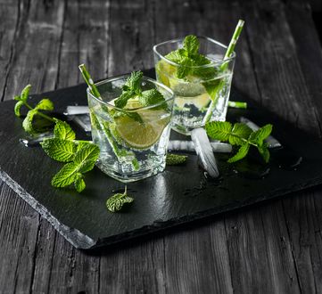 Обои на рабочий стол Два бокала с мохито с кусочками лайма, соломинками, листиками мяты и льдом