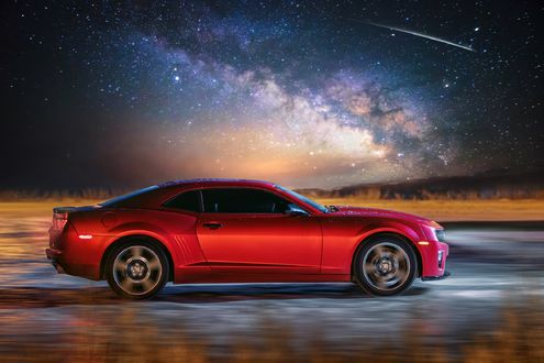 Обои на рабочий стол Красный Chevrolet Camaro едет по дороге на фоне млечного пути в ночном небе, фотограф doberman