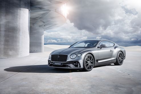 Обои на рабочий стол Серебристый Bentley Continental / Бентли Континенталь стоит у круглого здания под облачным небом